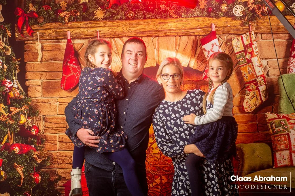 Vierköpfige Familie vor einer weihnachtlichen Studiokulisse.