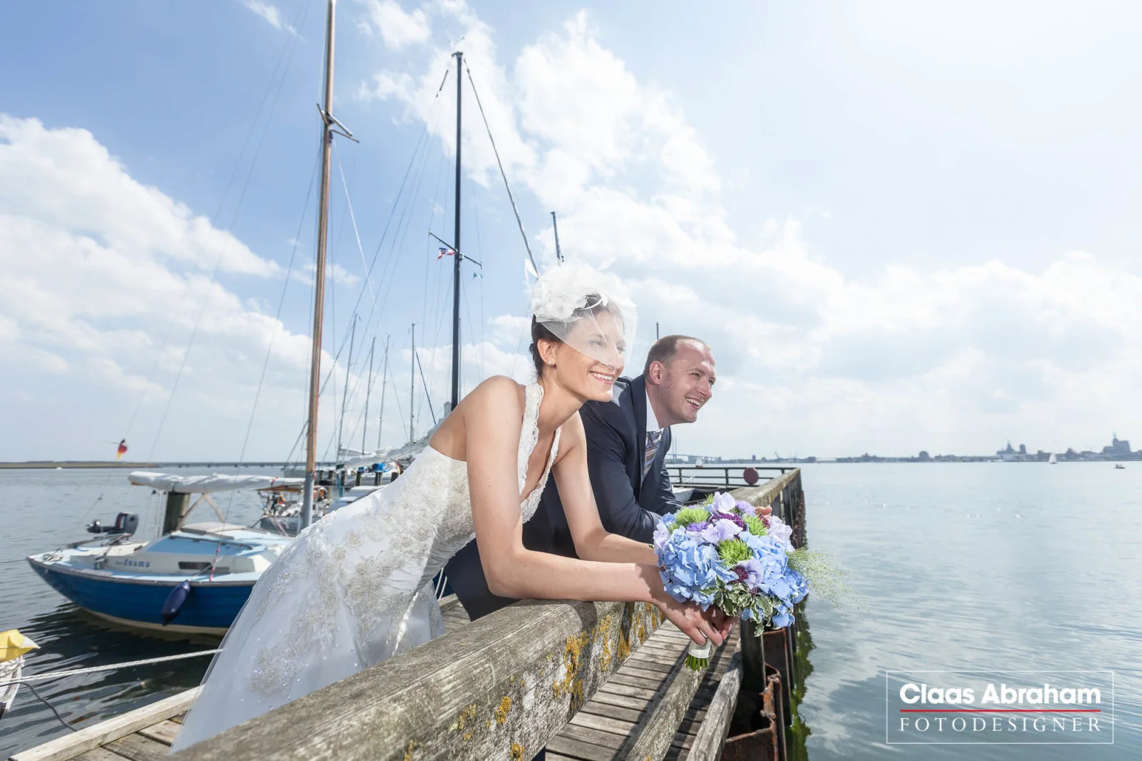 Hochzeitspaar am Wasser mit Blick über den Hafen.