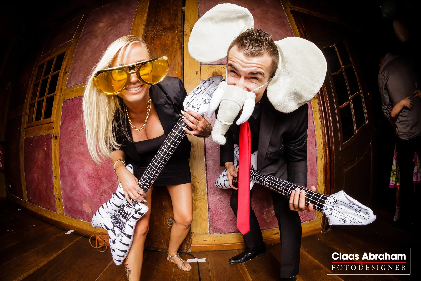 Zwei Gäste posieren mit großer Brille, Elefantenohren und aufblasbaren Gitarren.