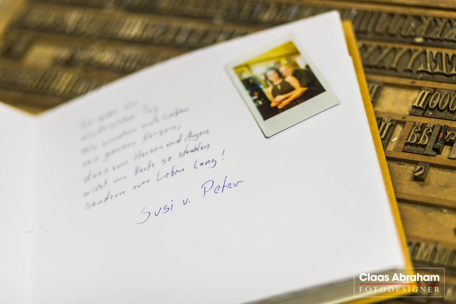 Geöffnetes Hochzeitsbuch mit eingeklebtem Sofortbild und handschriftlichem Gruß.