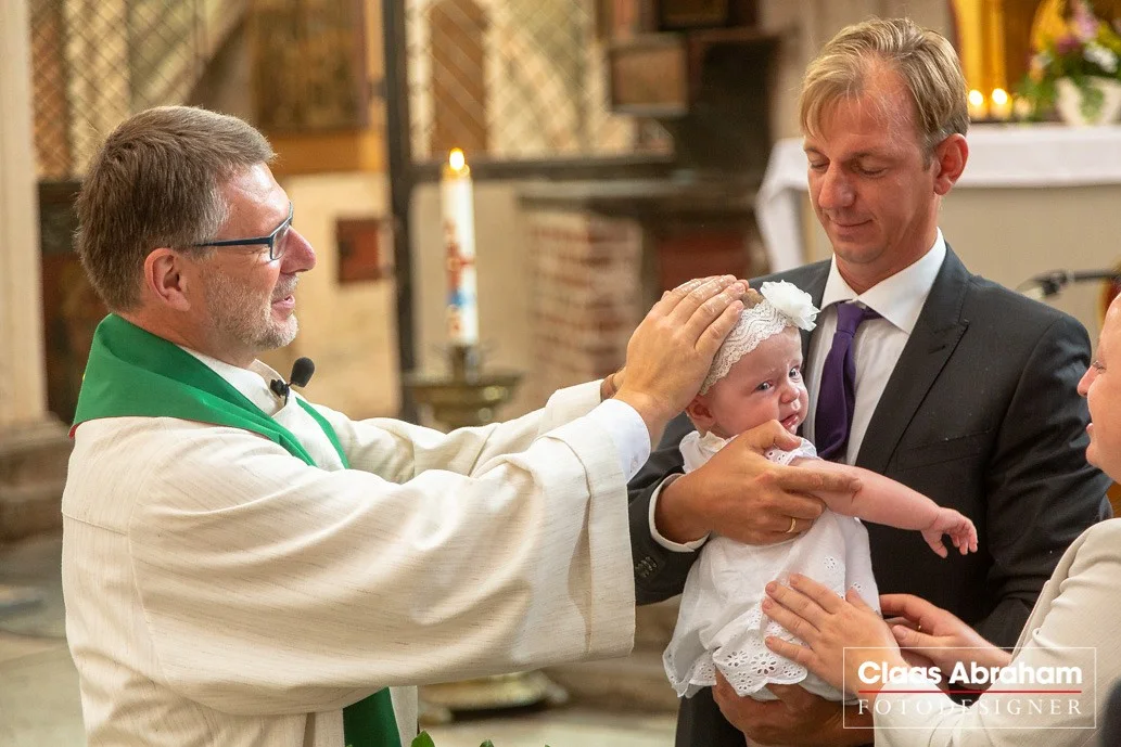 Familie mit dem Kind und Geistlichem während der Taufe.
