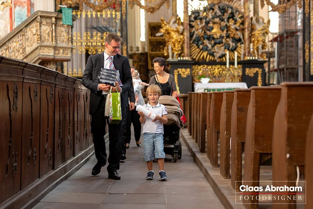 Familie auf dem Weg durch eine Kirche nach der Taufe.